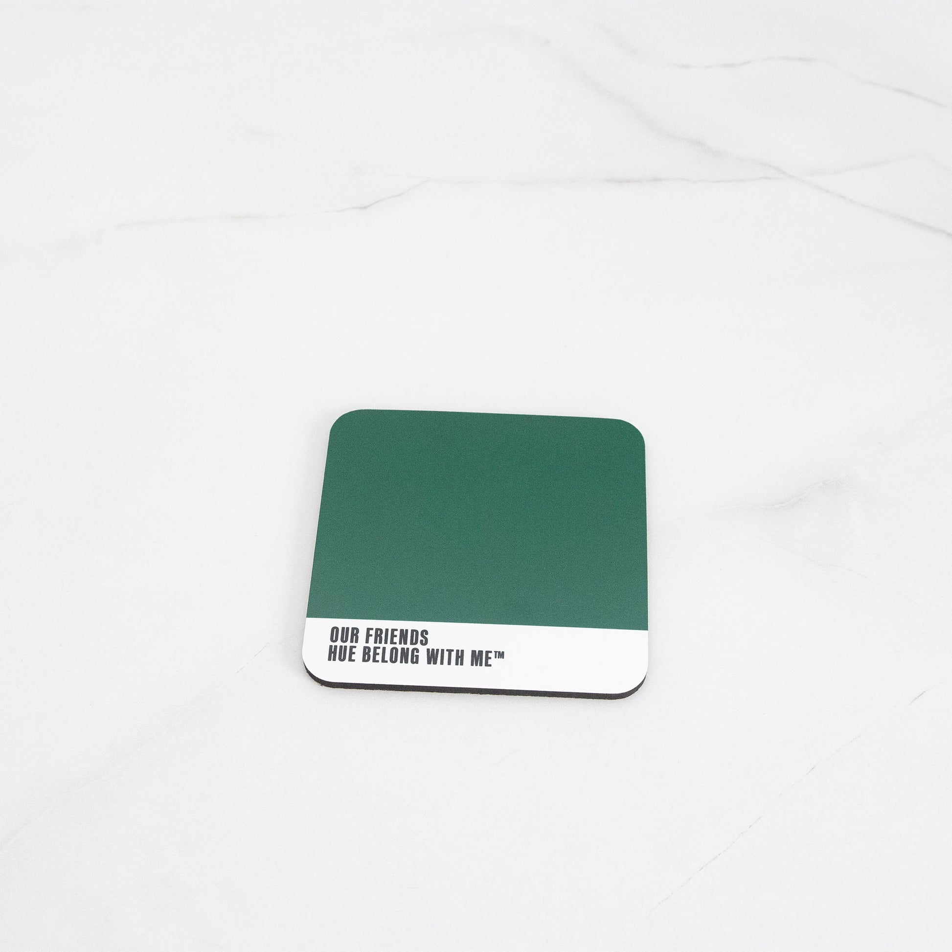Deep botanical evergreen cork-back coaster, flat lay on marble counter — Our Friends by Hue Belong With Me