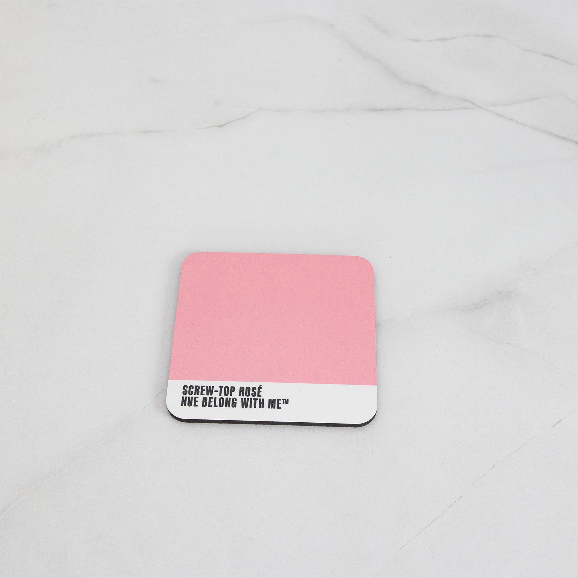 Warm nostalgic pink cork-back coaster, flat lay on marble counter — Screw Top Rosé by Hue Belong With Me
