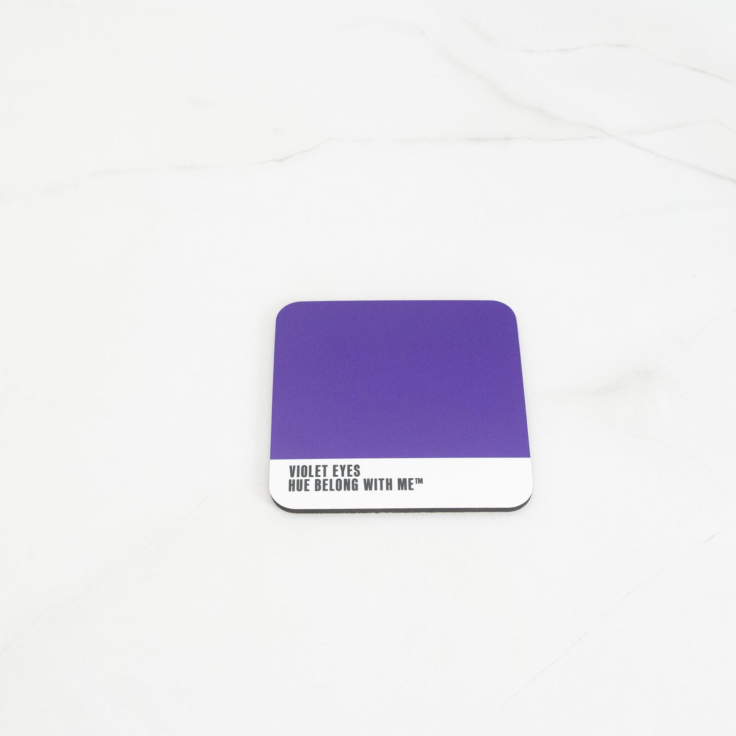 Deep commanding purple cork-back coaster, flat lay on marble counter — Violet Eyes by Hue Belong With Me